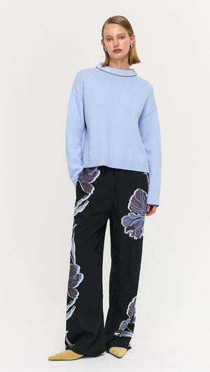 Model wearing a Blue Cotton Blend Contrast Seam Jumper with floral pants, showcasing a stylish look.