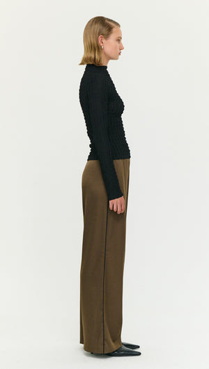Model wearing Espresso Relaxed Cut Silky Pant with a fitted black top in profile view.