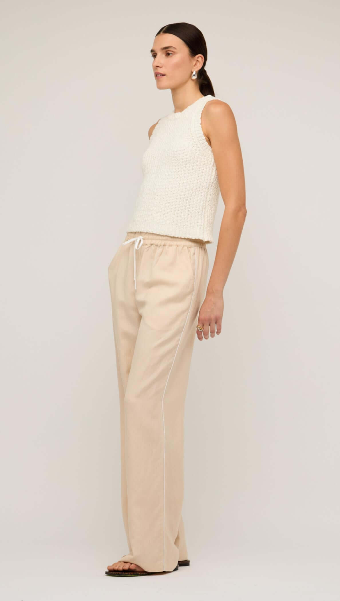 Model wearing beige relaxed linen wide-leg pants paired with a knitted tank top, showcasing casual yet stylish summer fashion.