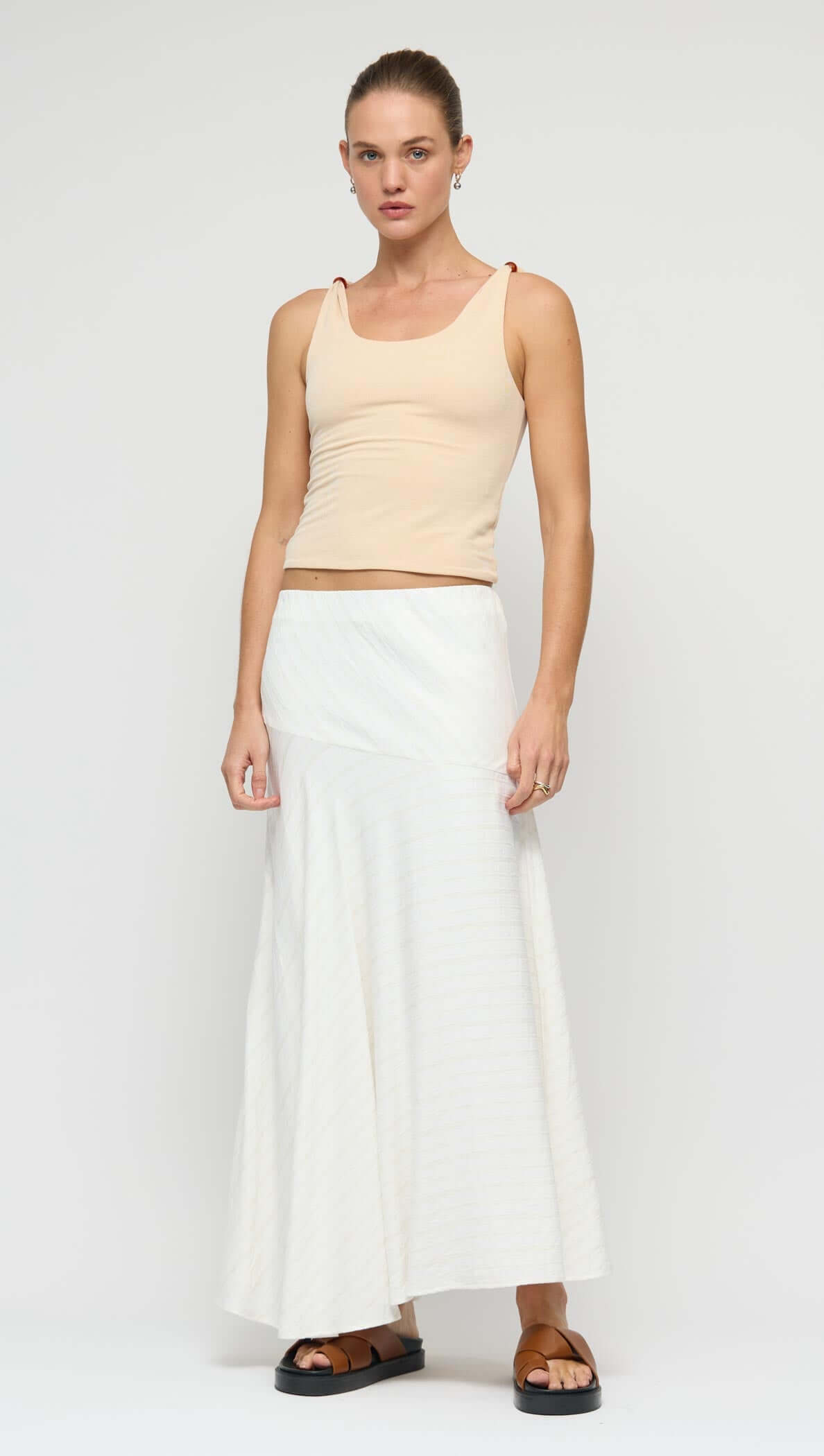 Asymmetric White Bias Maxi Skirt displayed on a model, showcasing its fluid silhouette and modern asymmetric waistband.