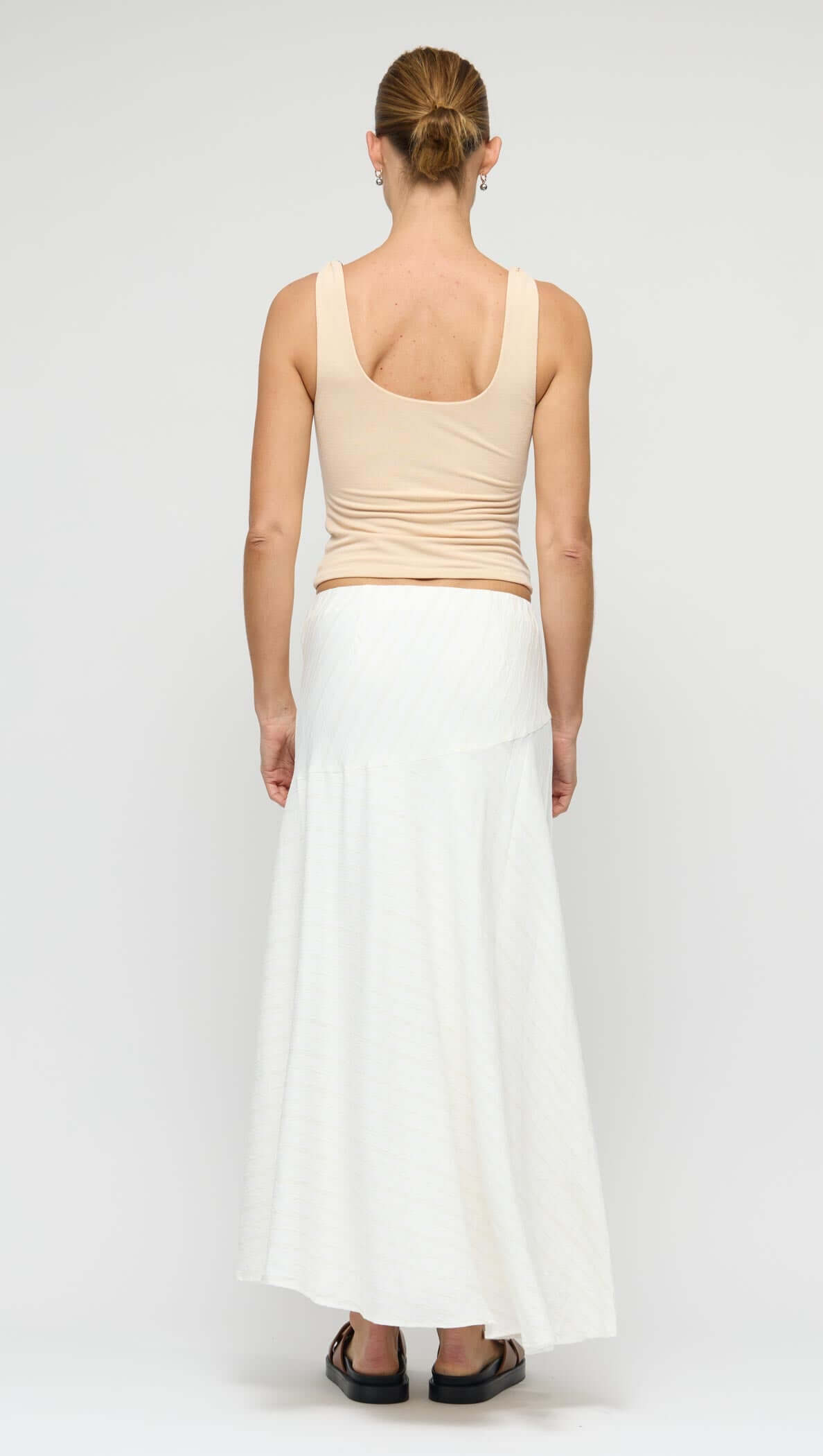 Model showcasing the Asymmetric White Bias Maxi Skirt from the back, highlighting its elegant drape and fluid silhouette.