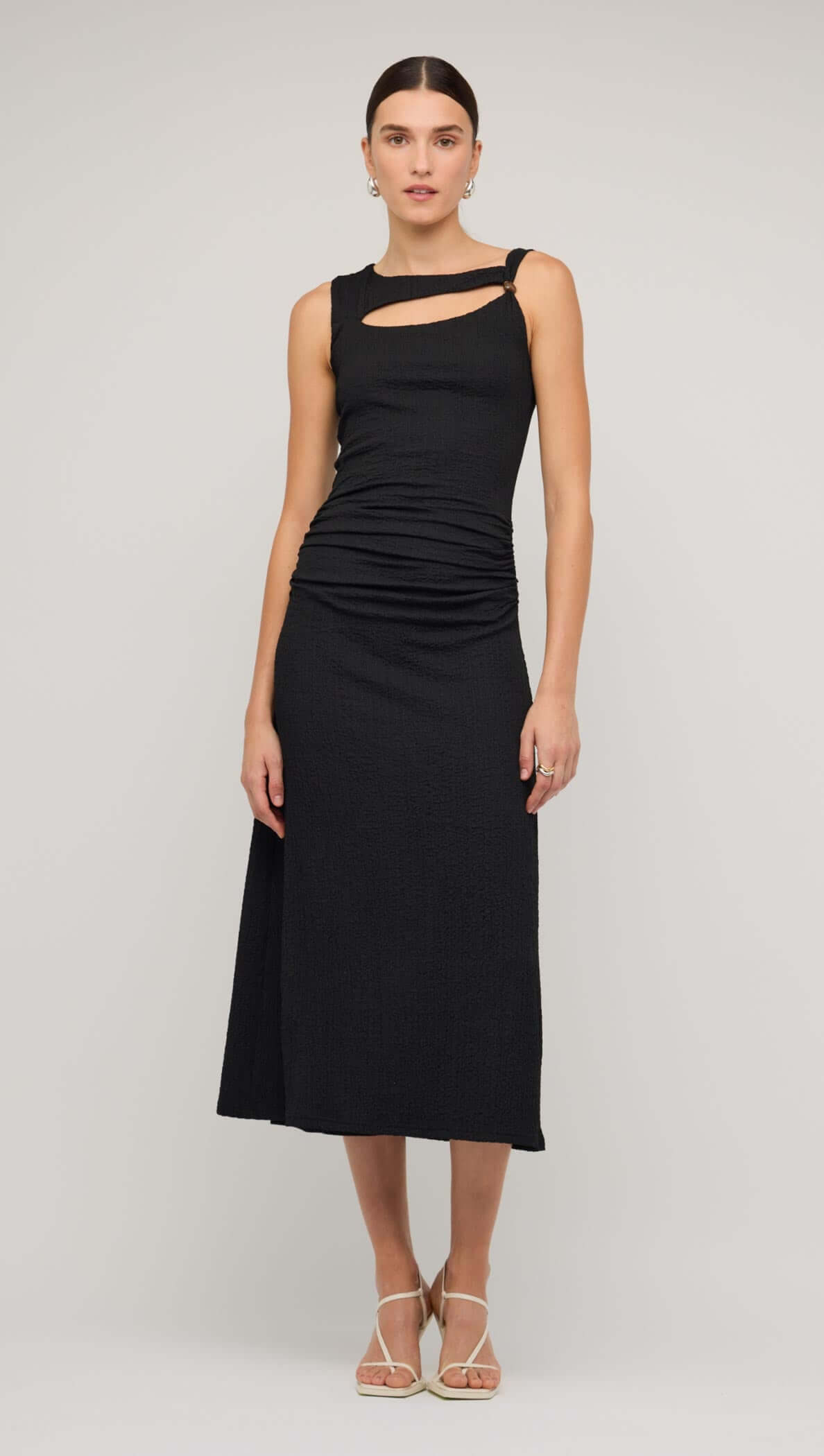 Model wearing a black cut out ruched A-line midi dress with bead detail, showcasing a sleek and sophisticated style.
