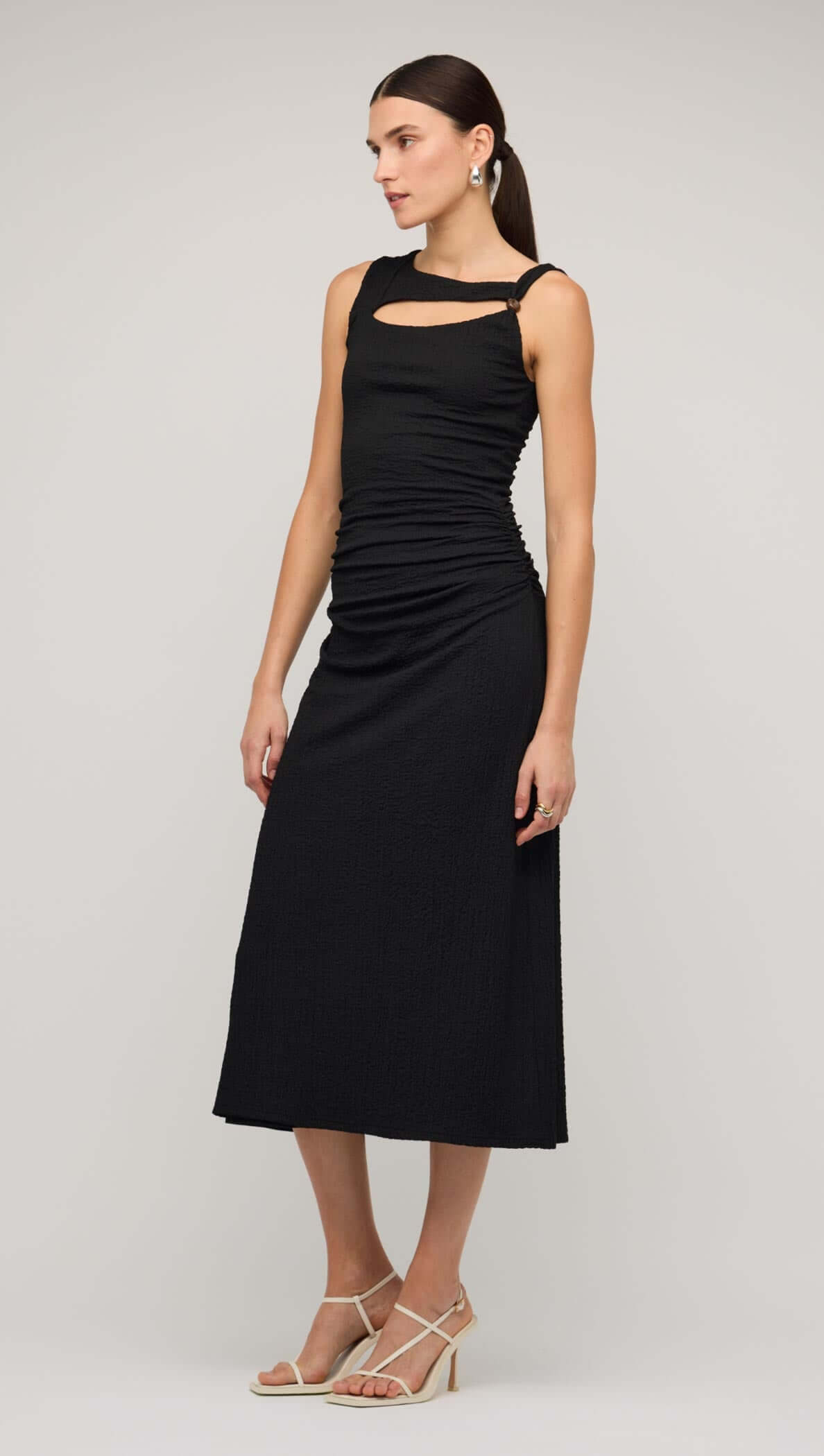Model wearing a black cut out ruched A-line midi dress with bead detail, showcasing a sleek and sophisticated style.
