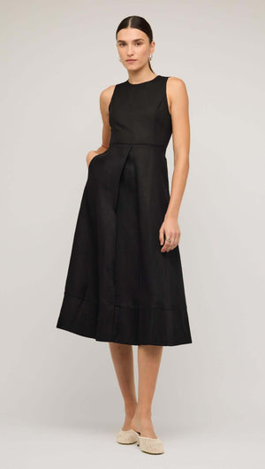 Black linen A-line midi dress with sleeveless design and subtle pleats, modeled by a woman on a neutral background.
