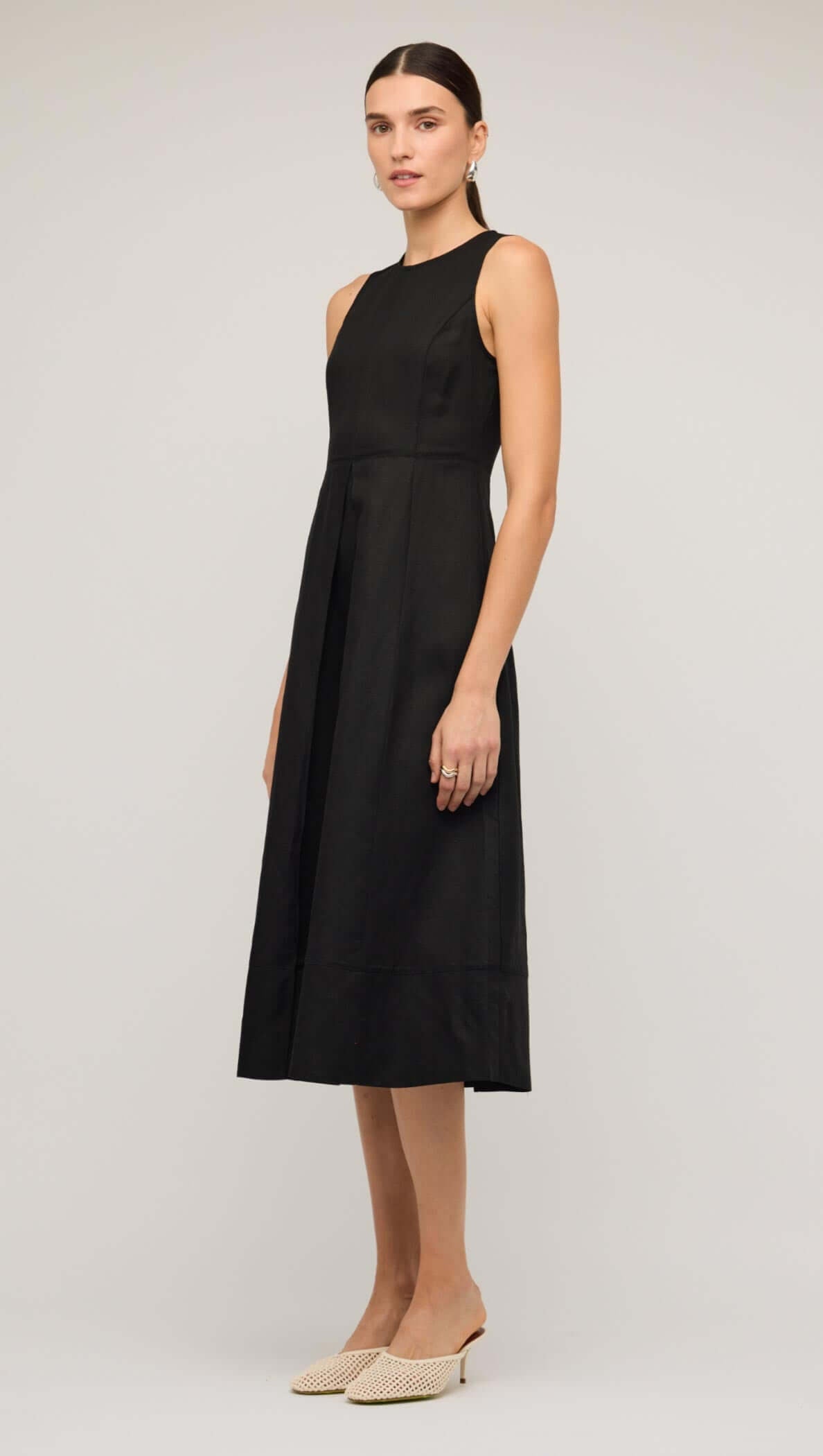 Model wearing a black linen A-line midi dress, showcasing its elegant design and modern silhouette.