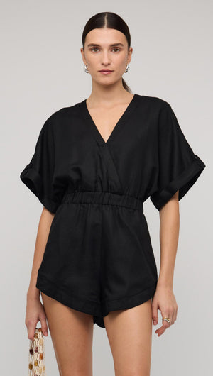 Black linen blend V-neck playsuit worn by a model, featuring a relaxed fit and short sleeves.