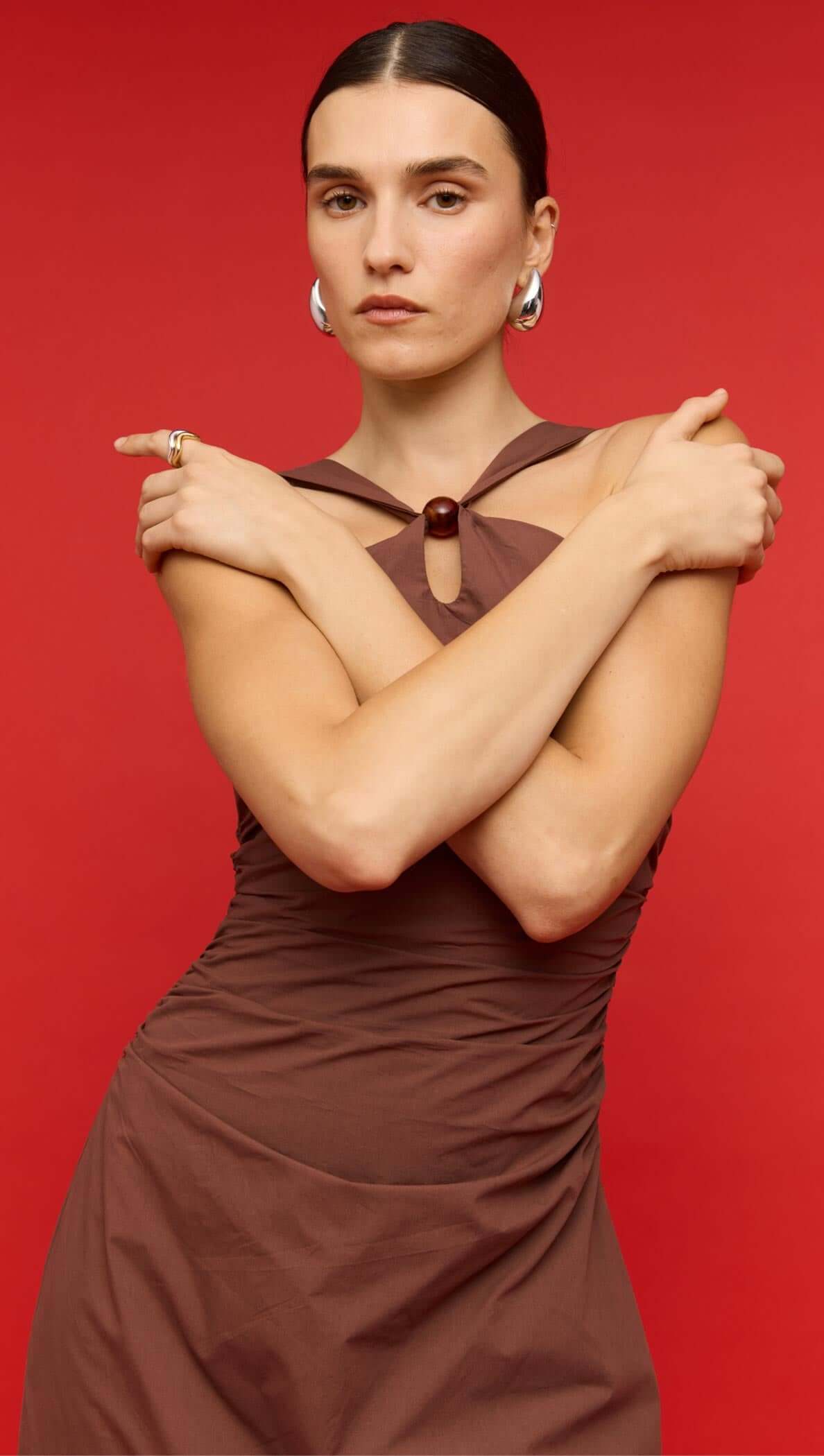 Model wearing a brown cotton bead halter-neck ruched midi dress, accessorized with sunglasses and a clutch.