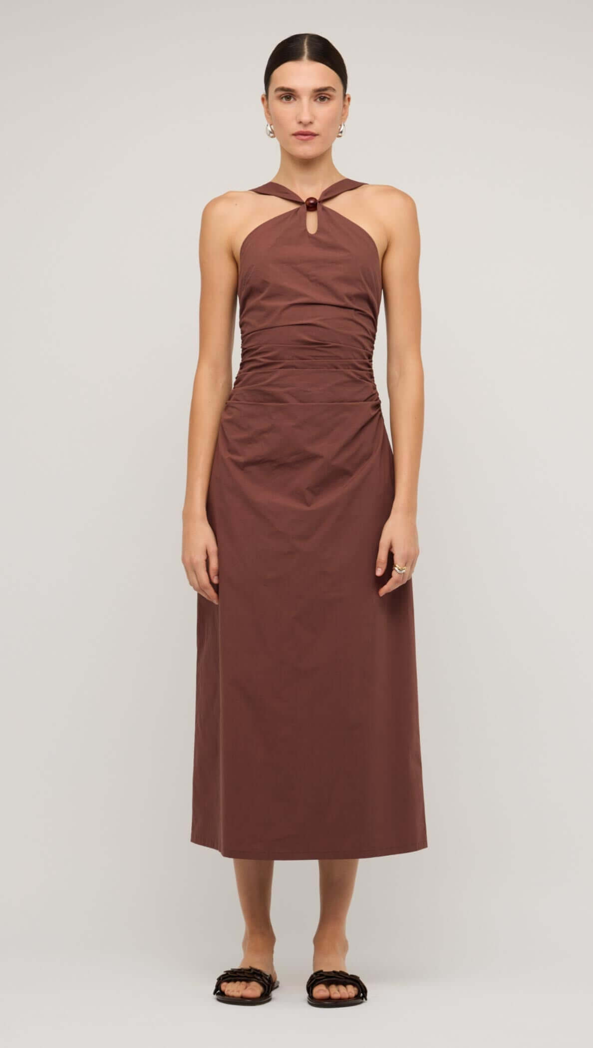 Model wearing a brown cotton bead halter-neck ruched midi dress, showcasing its elegant design.