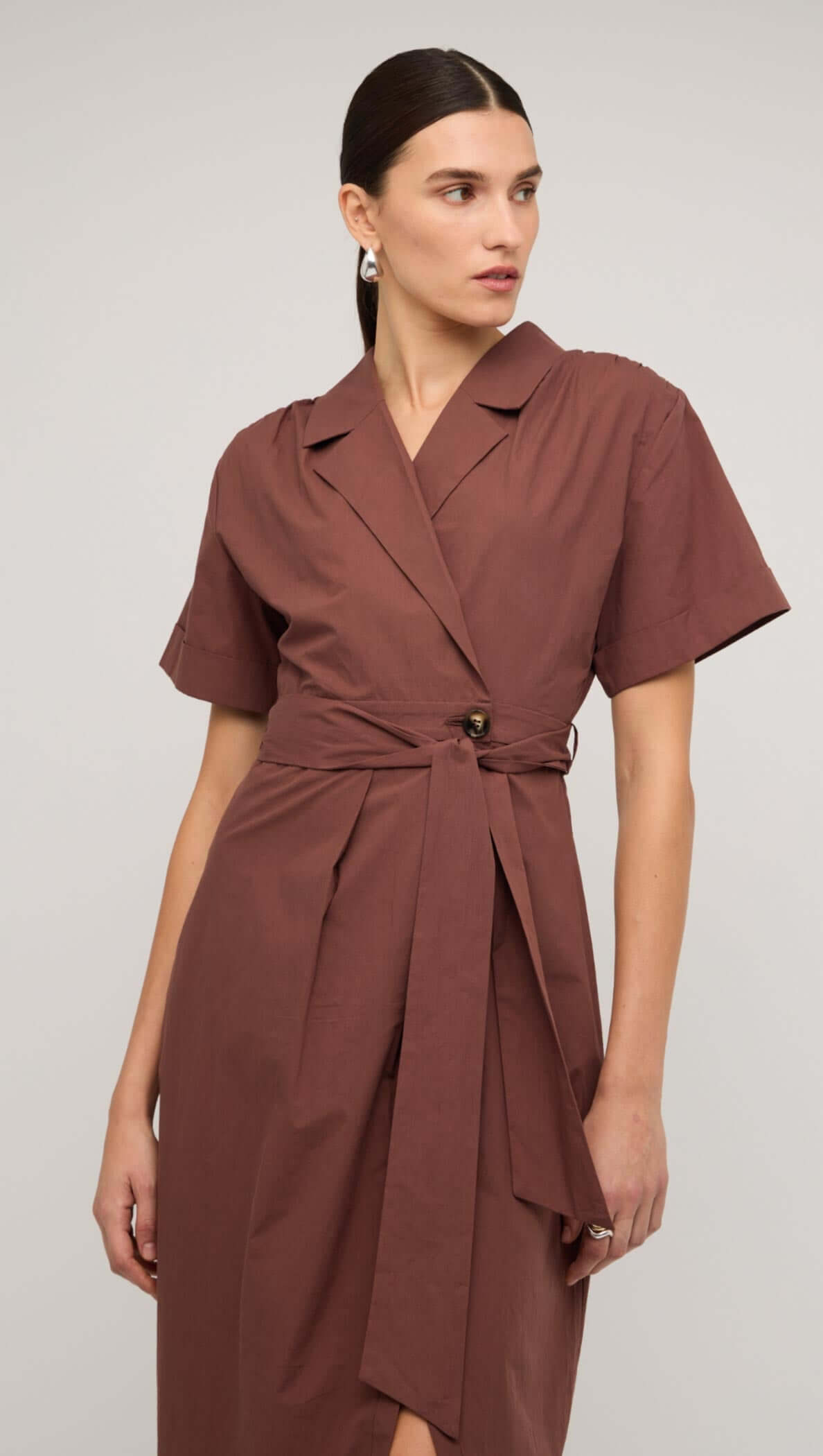 Brown cotton wrap midi shirt dress with short sleeves and a side slit, styled with elegant heels.