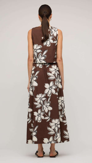 Back view of a woman wearing a brown and white floral crop top styled with a matching maxi skirt.
