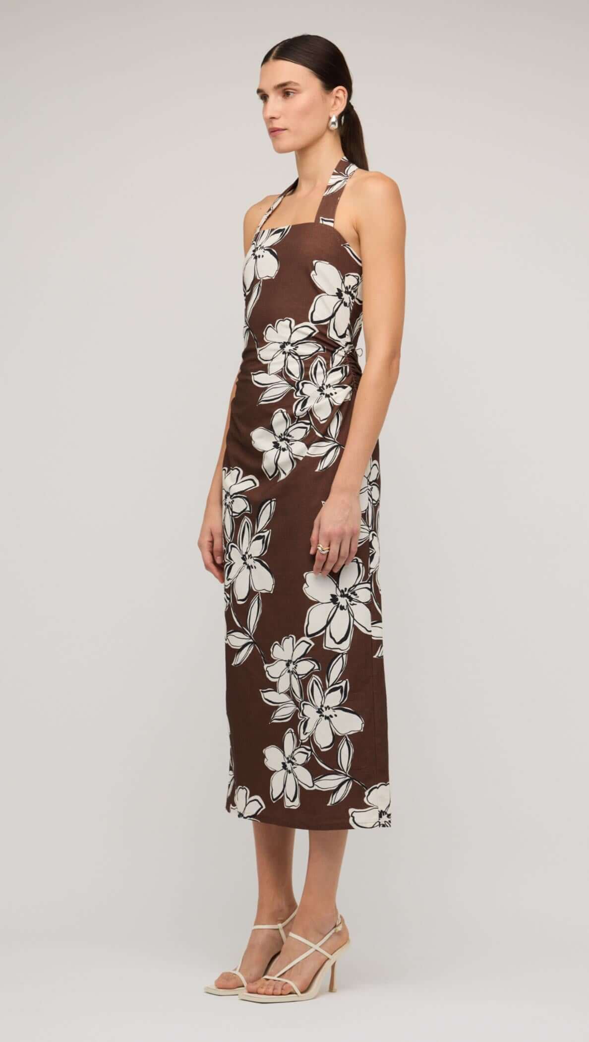 Model wearing a brown and white floral halter-neck midi dress, showcasing a stylish summer look.