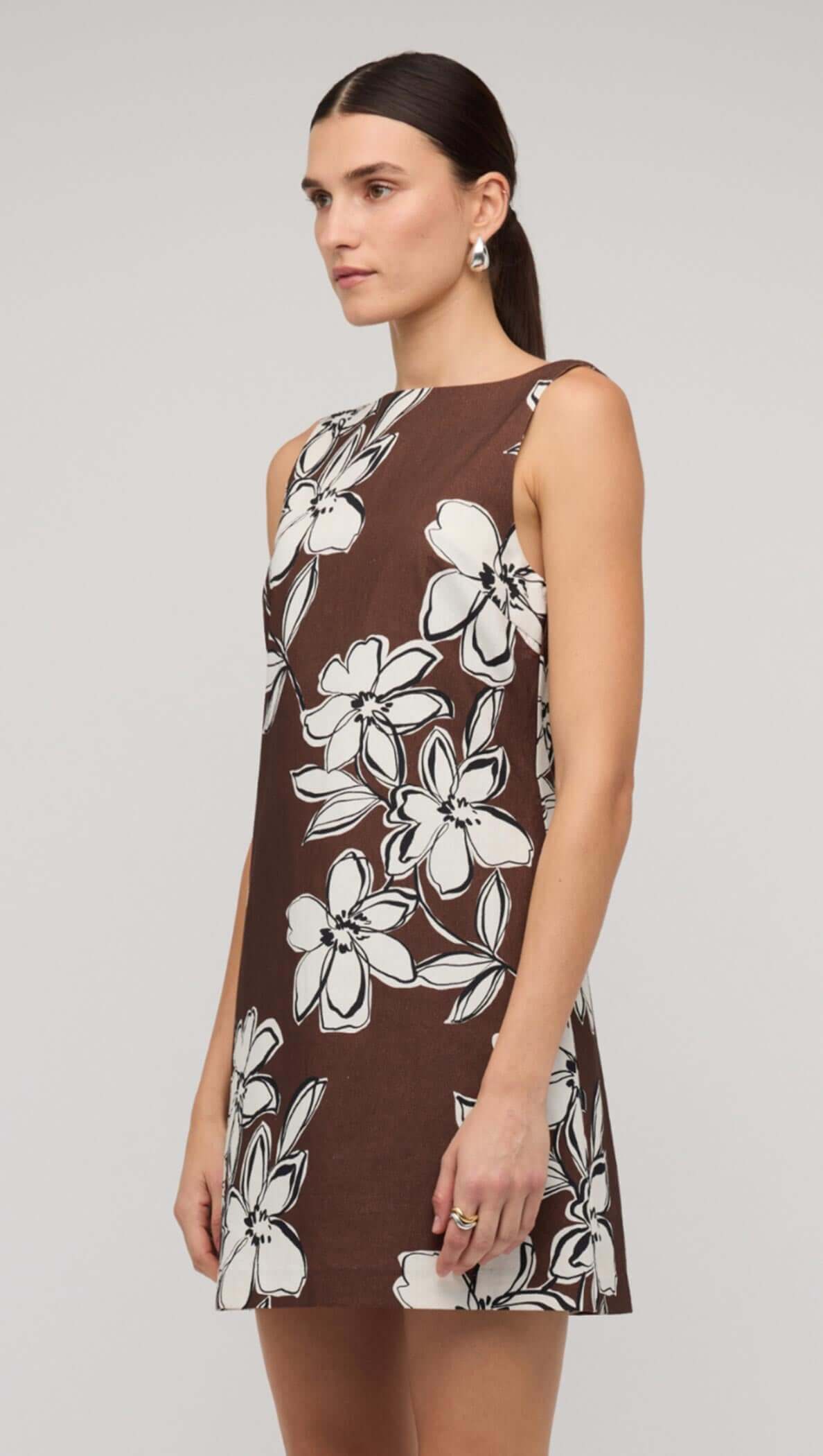 Brown and white floral shift mini dress showcasing a model wearing a sleeveless design with a playful, polished style.