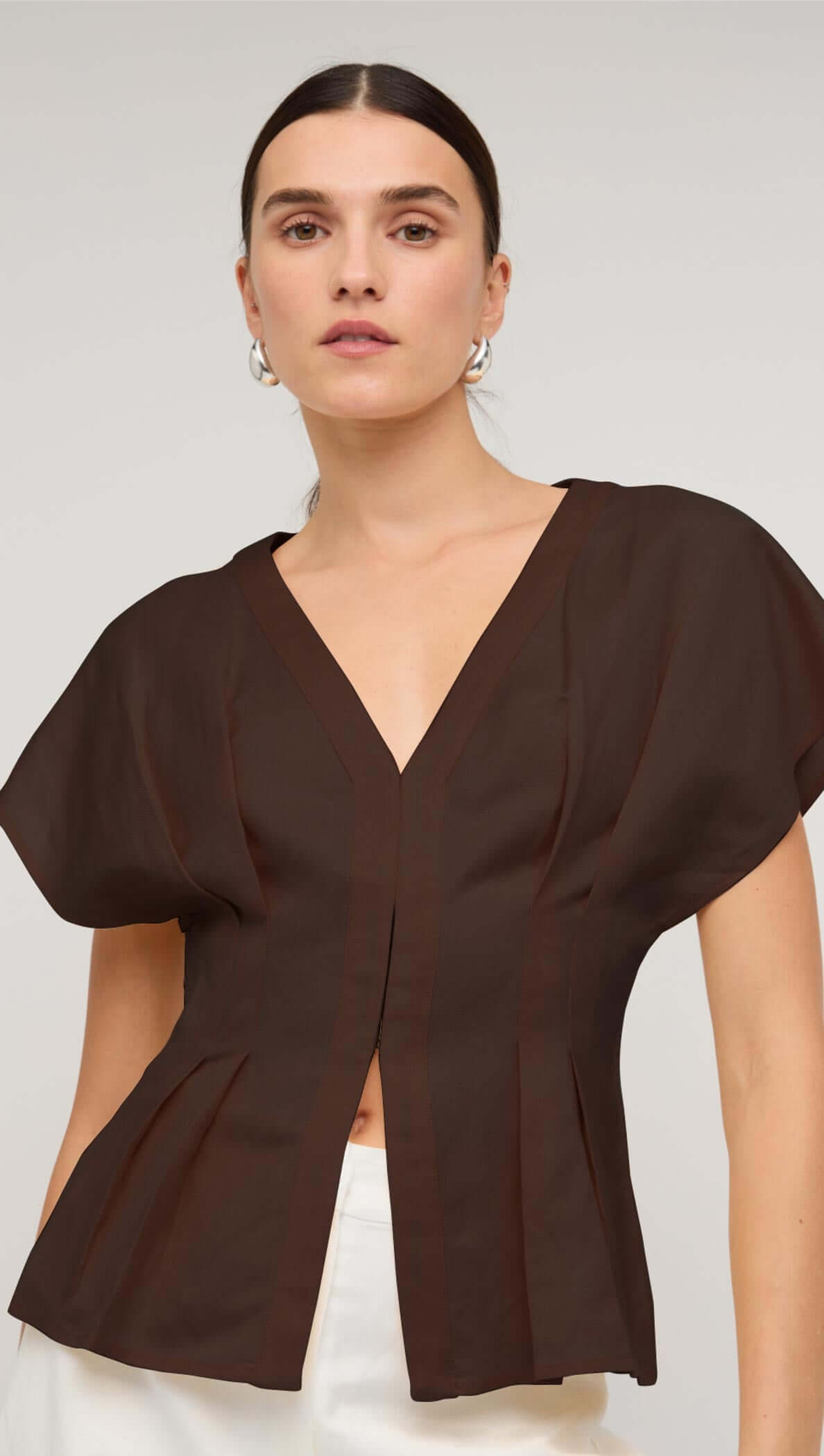 Chocolate brown linen pleated V-neck blouse on model, showcasing elegant design and contemporary style.