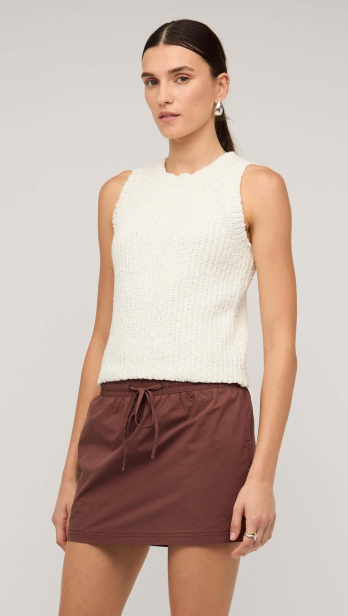 Model wearing a white knit tank top paired with a brown drawstring skirt, showcasing a stylish casual look.