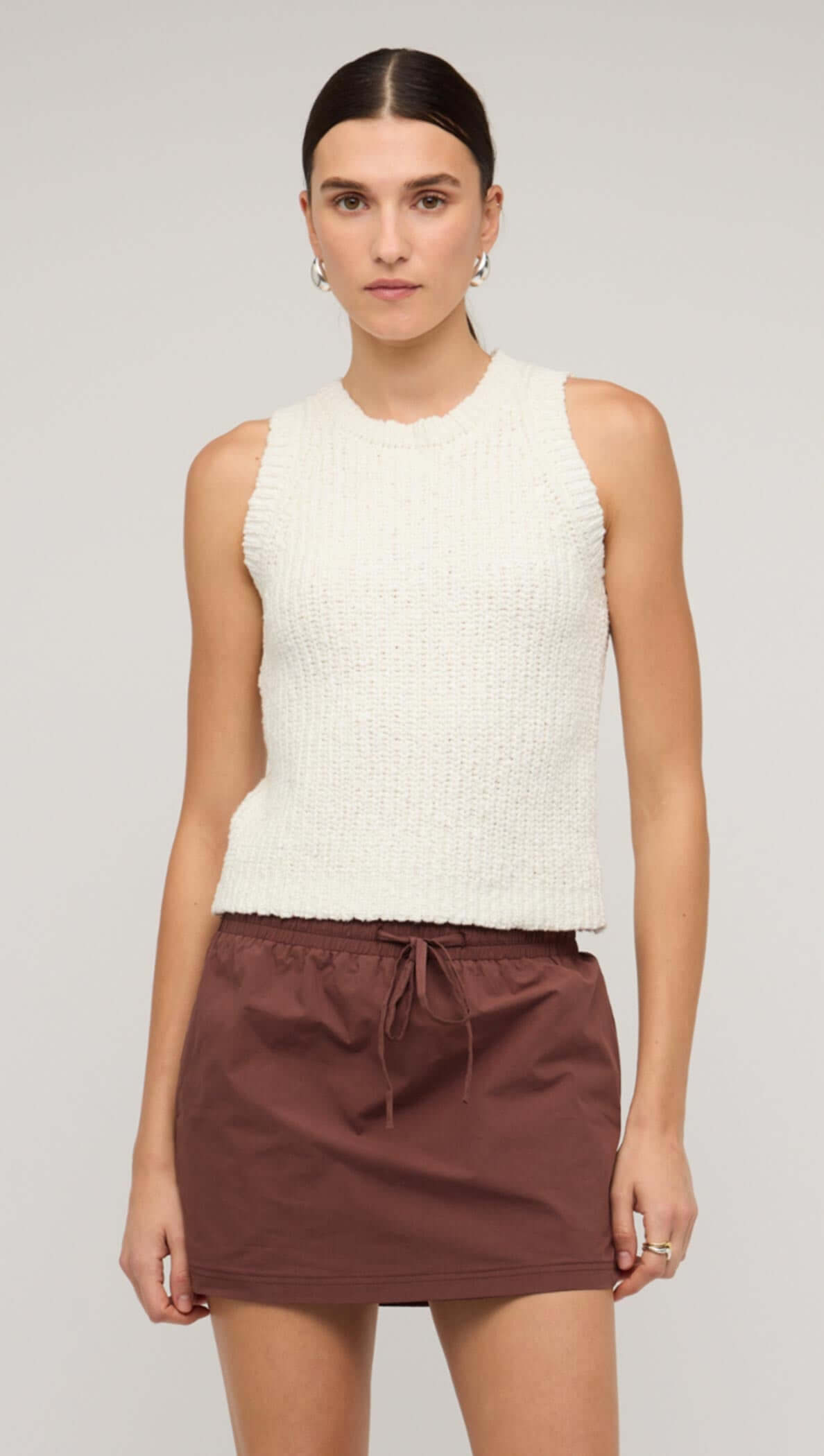 Model wearing a white knit tank top paired with a brown drawstring skirt, showcasing a stylish casual look.
