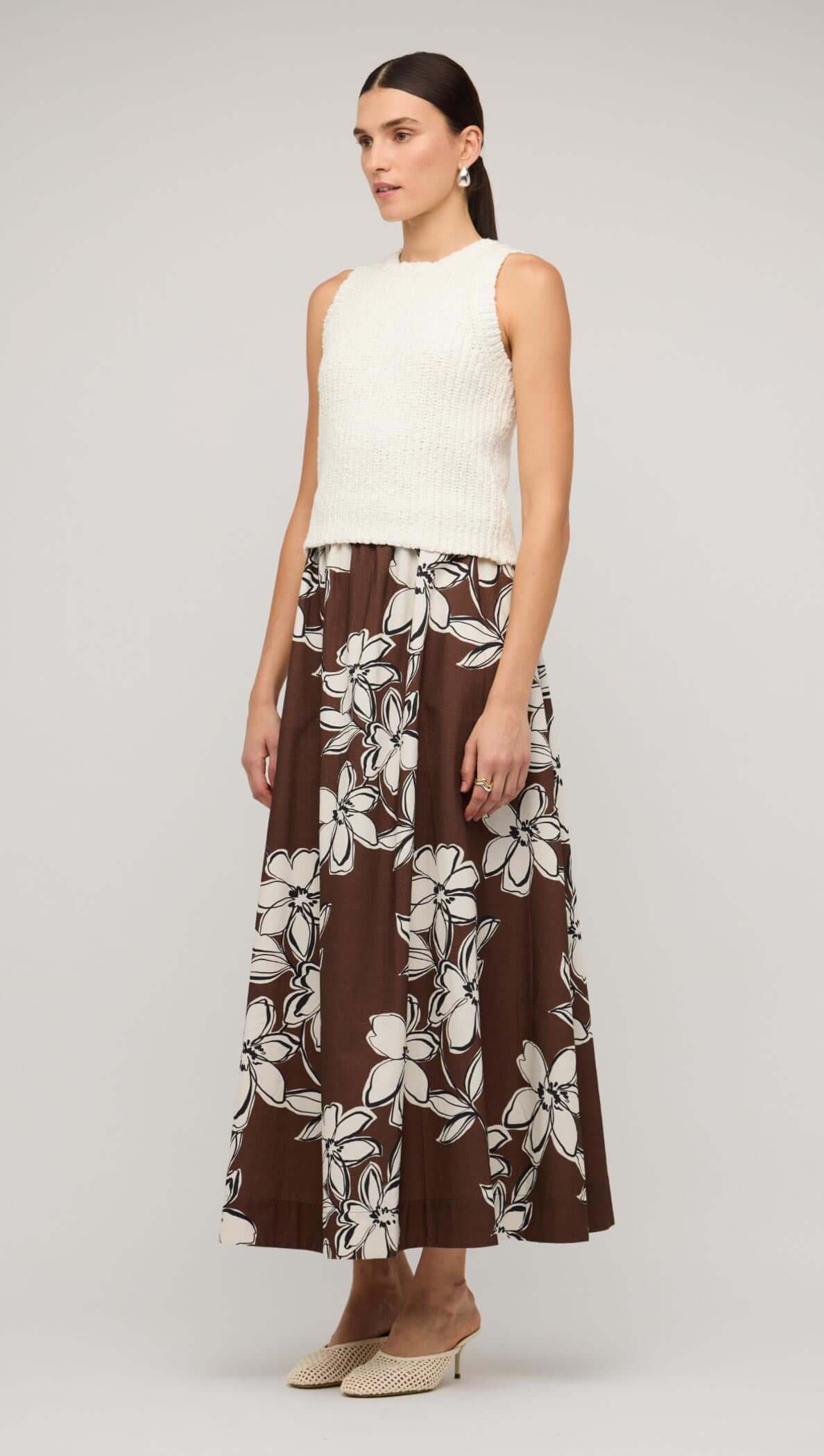 Model wearing a white knit tank top paired with a brown floral maxi skirt, showcasing a stylish and comfortable summer outfit.