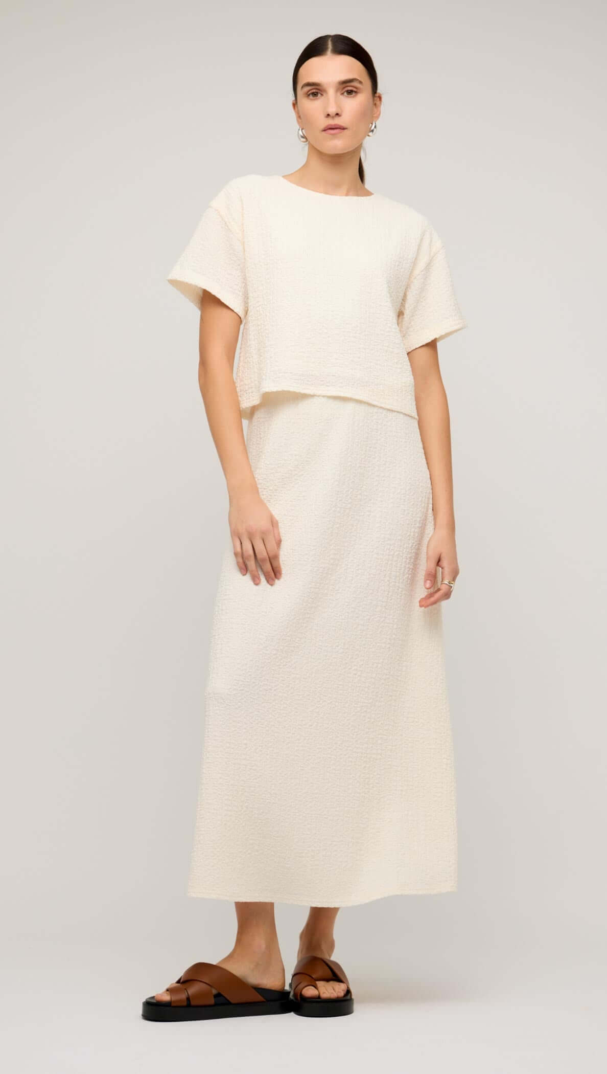 Model wearing a cream boxy short sleeve cropped top with a matching maxi skirt and stylish sunglasses.