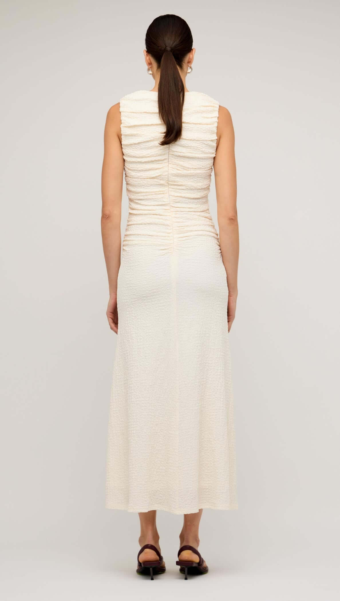 Back view of a cream gathered v-neck A-line midi dress showcasing a sleek design and fitted silhouette.