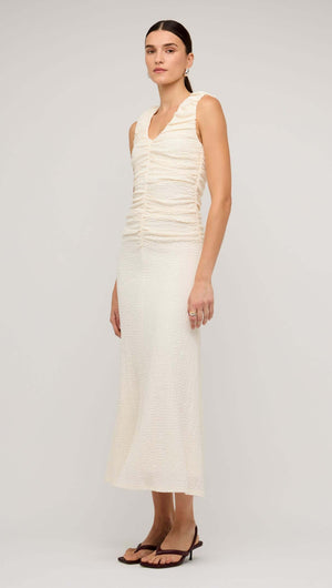 Model wearing a cream gathered V-neck A-line midi dress, showcasing a sleek, feminine silhouette and delicate ruching.
