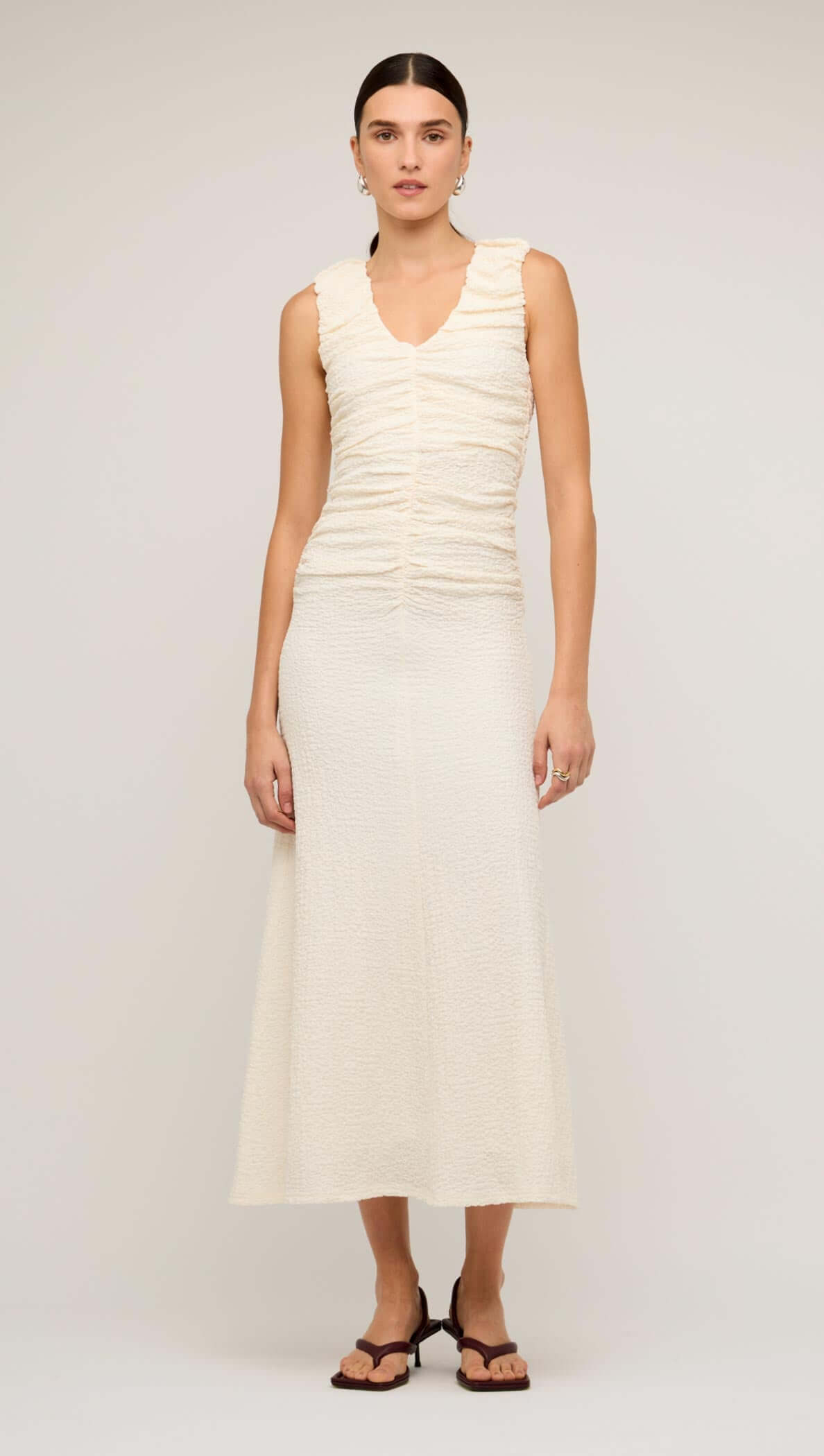 Cream gathered v-neck A-line midi dress on model, showcasing a sleek and feminine silhouette.
