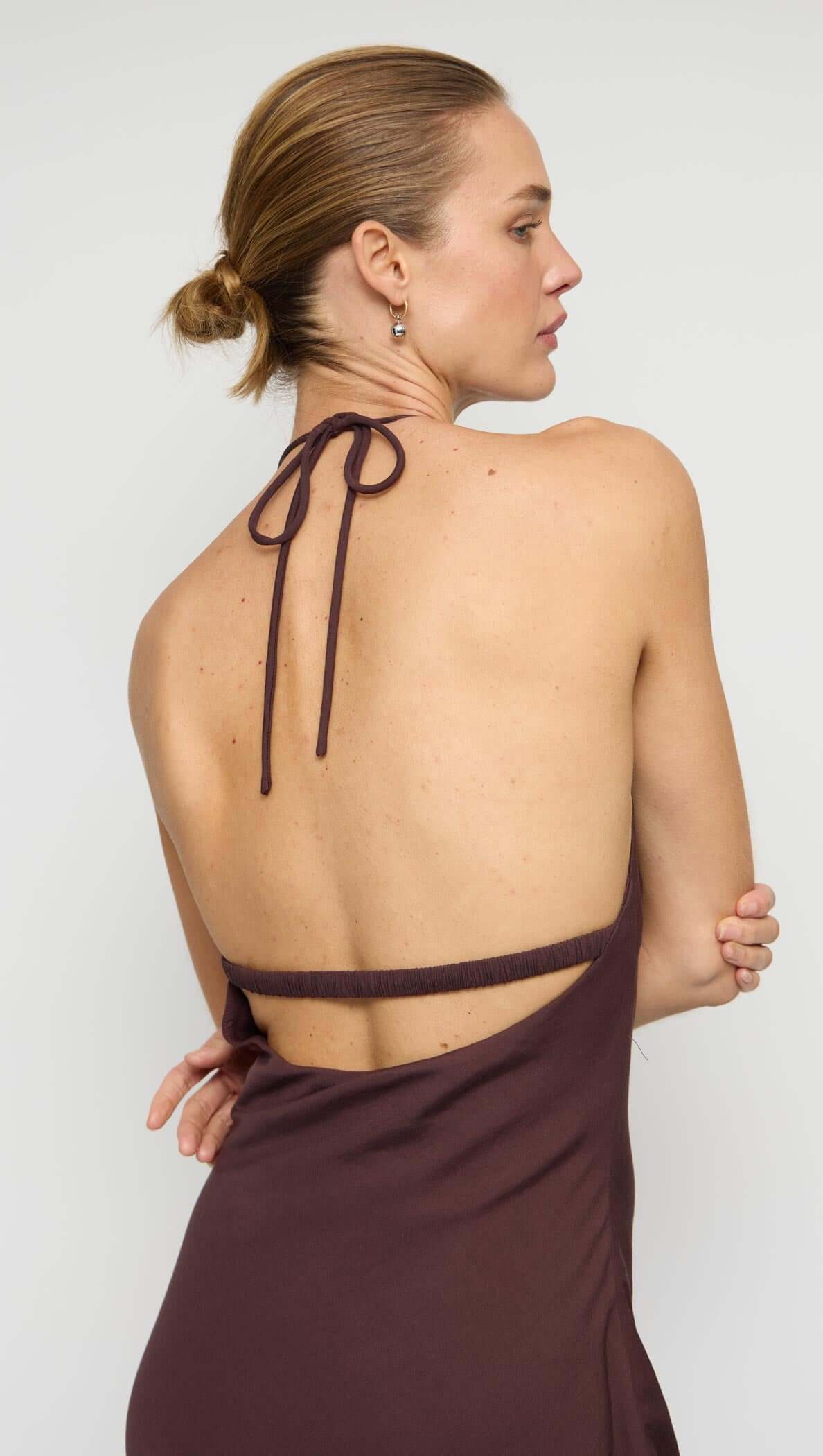 Model showcasing the back of the Chocolate Halter Midi Dress with tie detail and open back style.