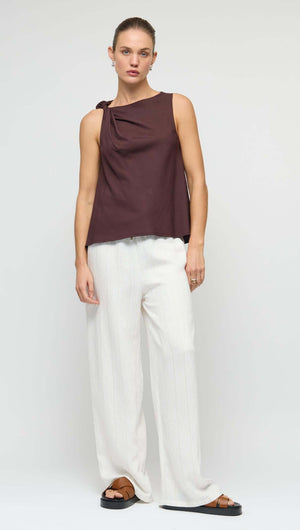 Model wearing a Chocolate Twist Top with shoulder knot detail, paired with white wide-leg pants, showcasing a relaxed fit.