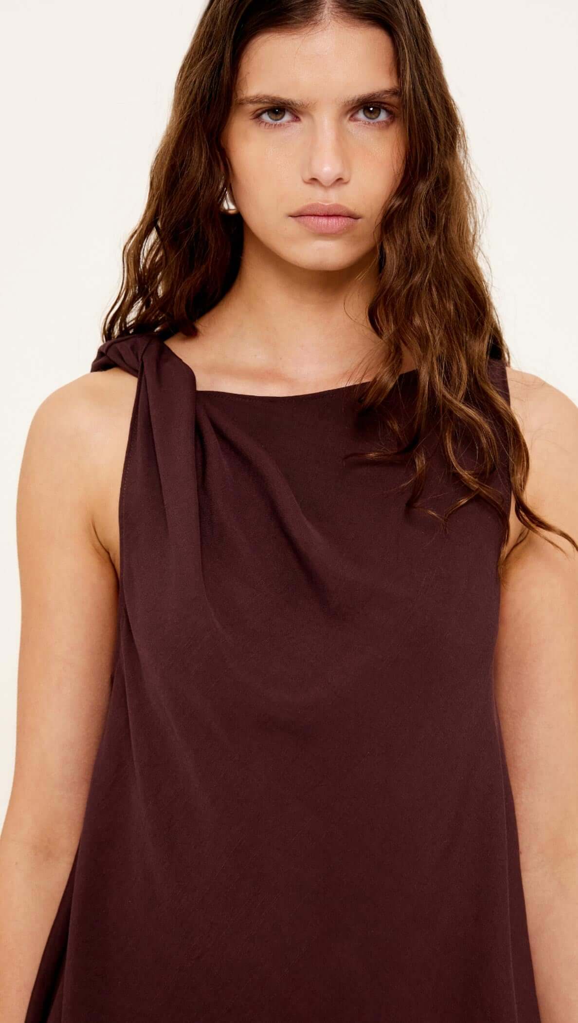 Model wearing the Elira Chocolate Twist Top with shoulder knot detail and soft drape neckline.