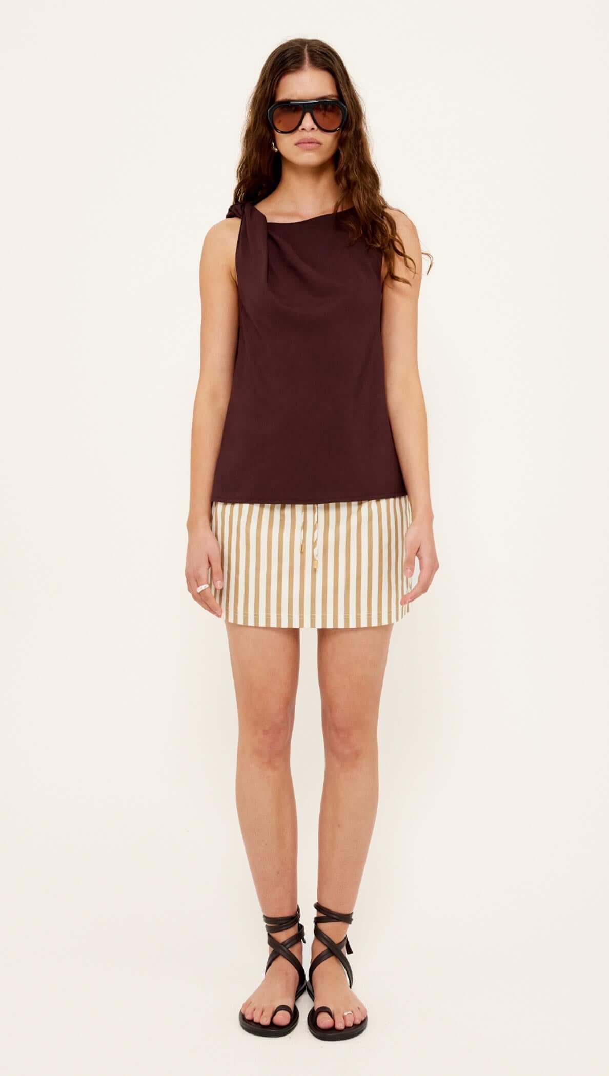 Model wearing Chocolate Twist Top paired with striped skirt and stylish sandals for a chic summer look.