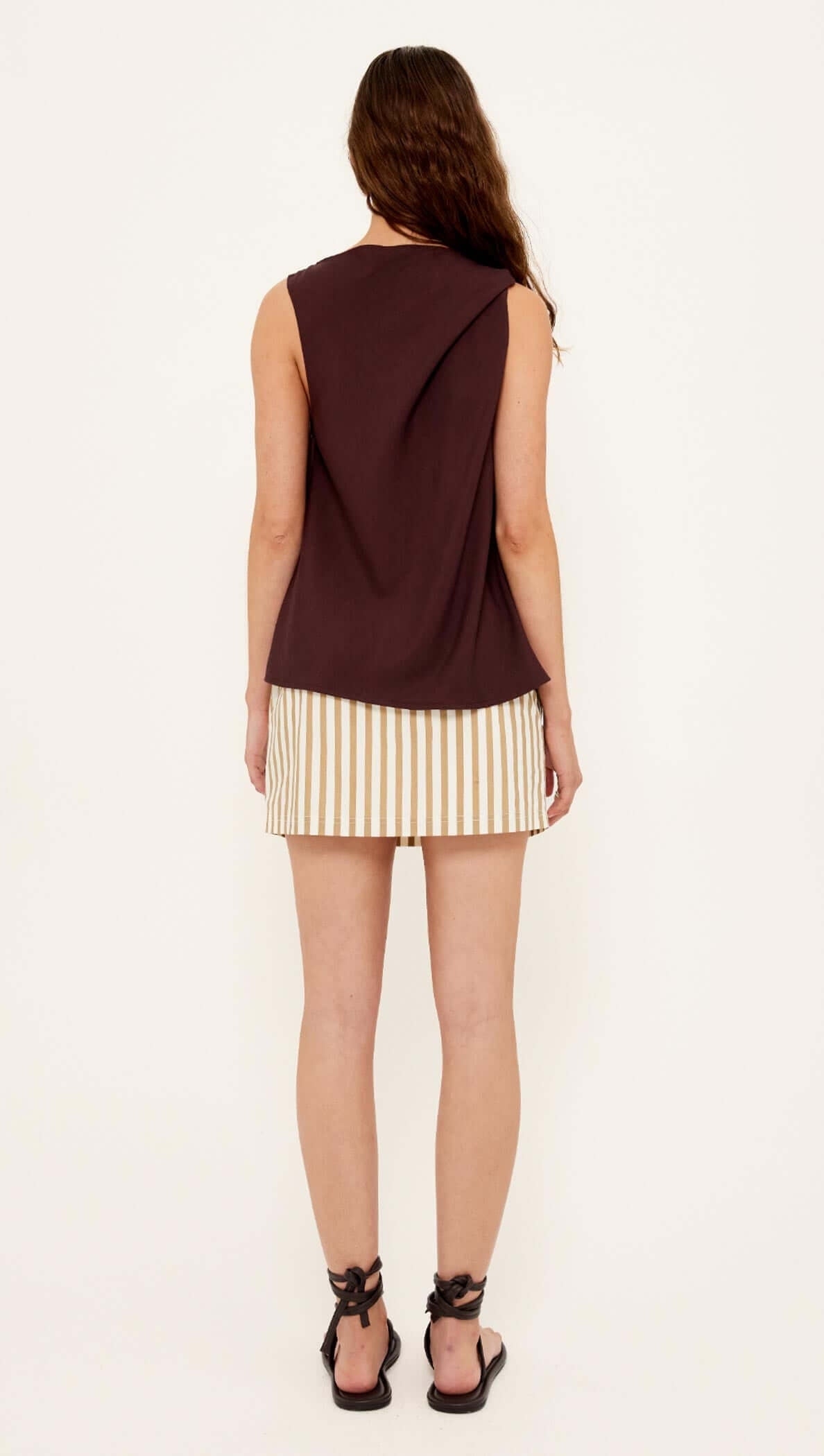 Back view of the Chocolate Twist Top paired with a striped skirt, showcasing the shoulder twist detail.