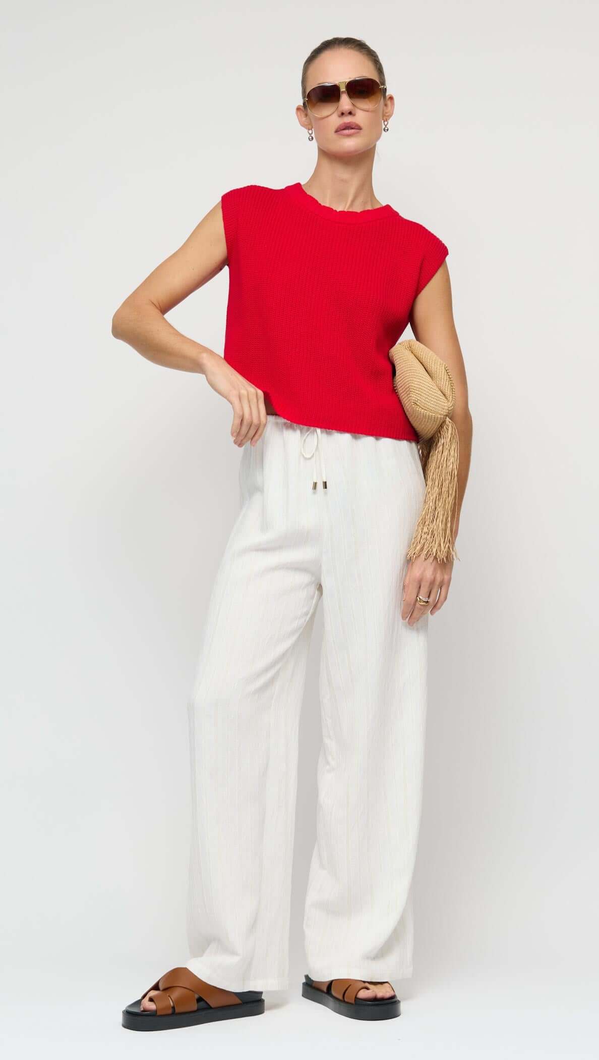 Model wearing a Cotton Blend Red Knit Tank Top paired with white pants and sunglasses.