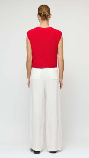 Back view of a model wearing a Cotton Blend Red Knit Tank Top with white wide-leg pants.