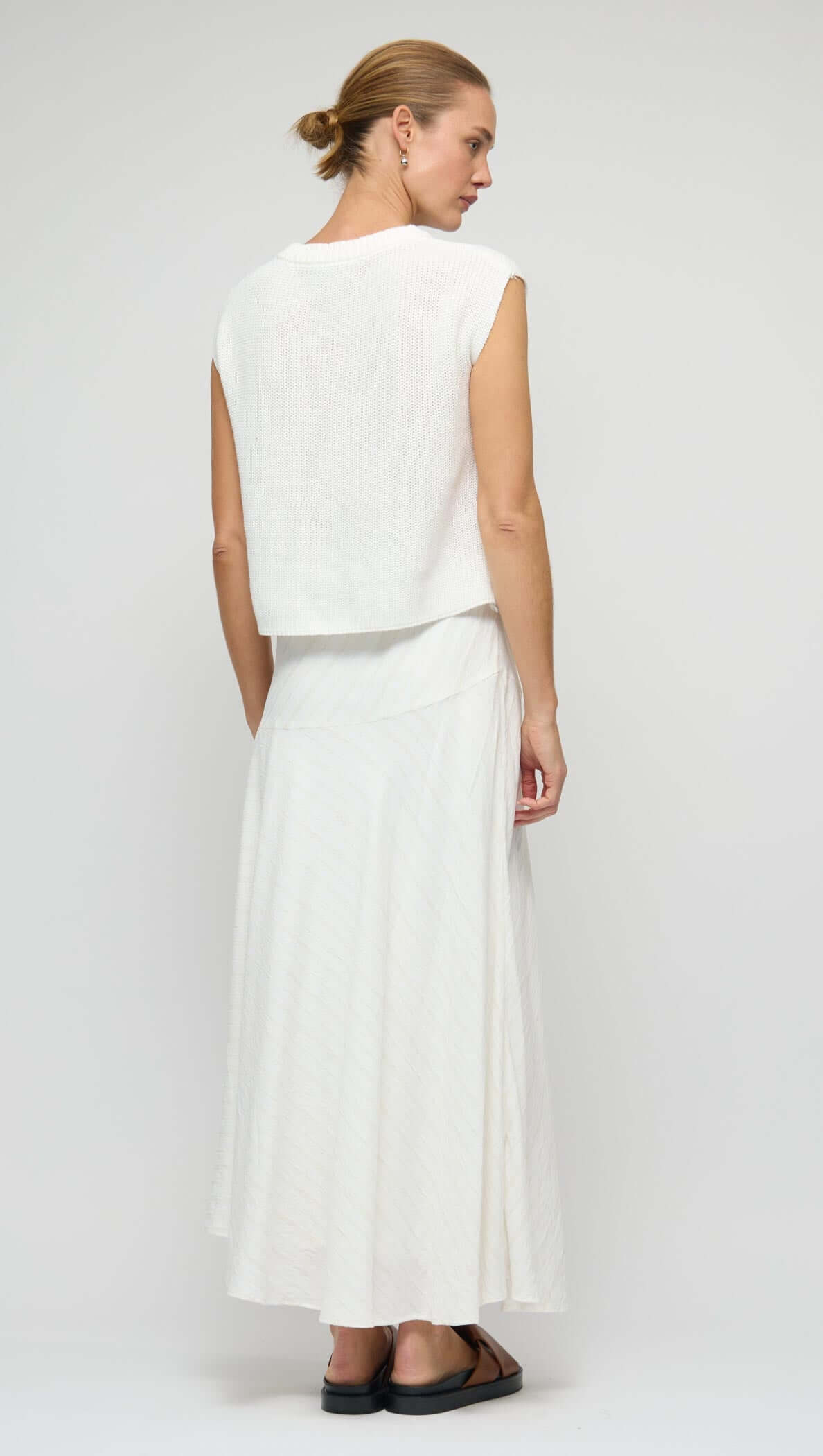 Back view of model wearing a Cotton Blend White Knit Tank Top paired with a flowing skirt.