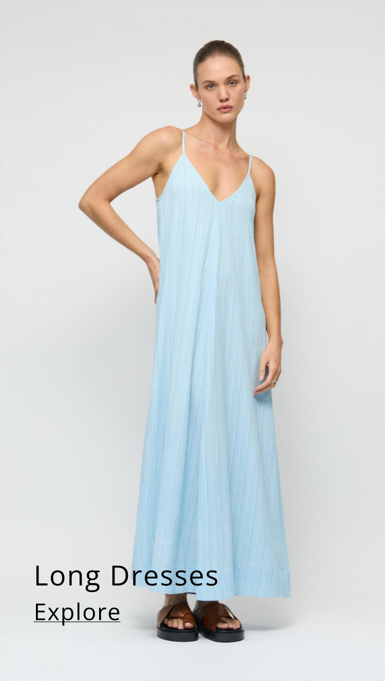 Woman wearing a light blue dress on a white background with text 'Long Dresses Explore'.