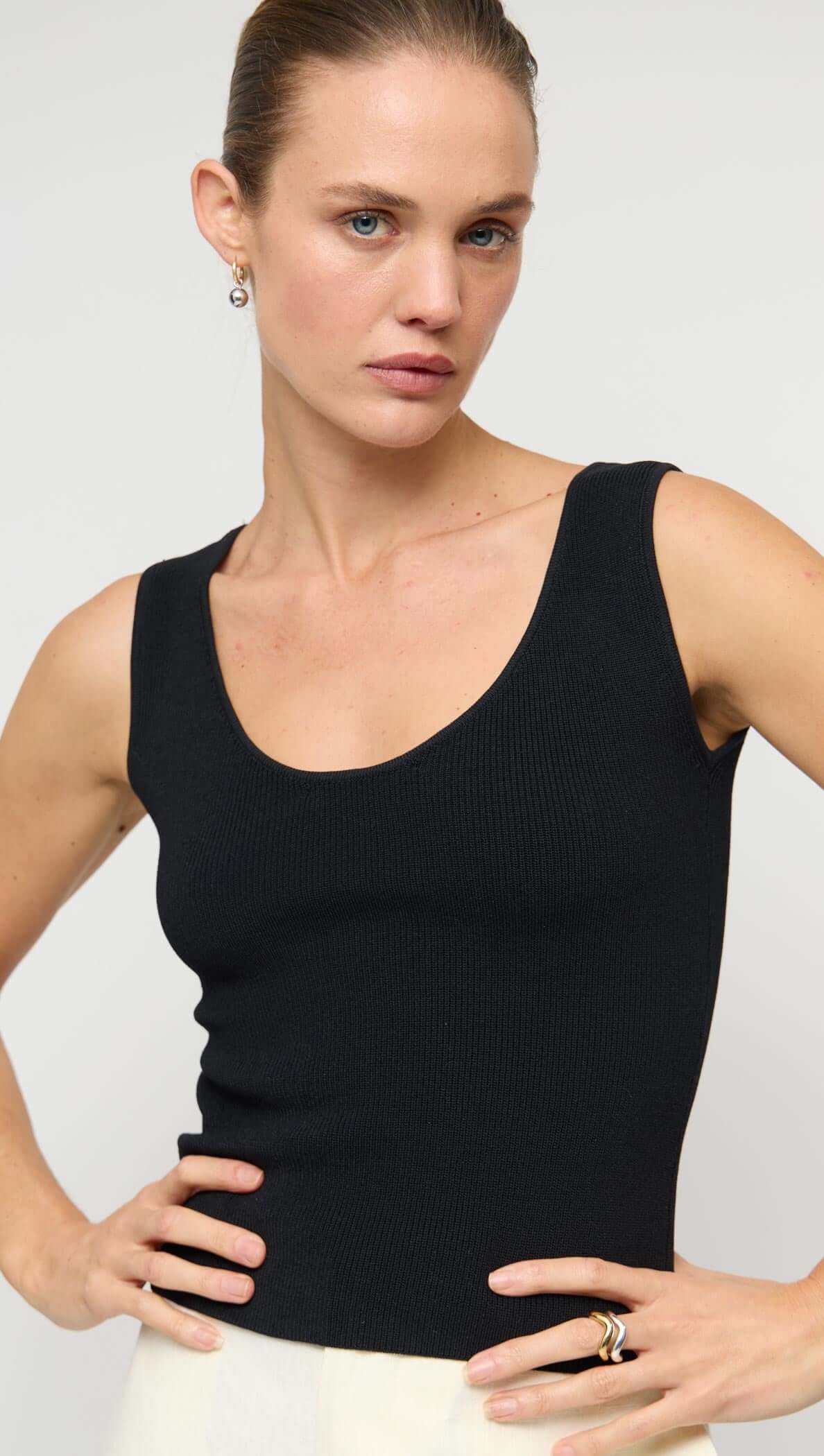 Model wearing a stylish Reversible Black Knit Tank Top with a scoop neckline, showcasing its fitted silhouette.