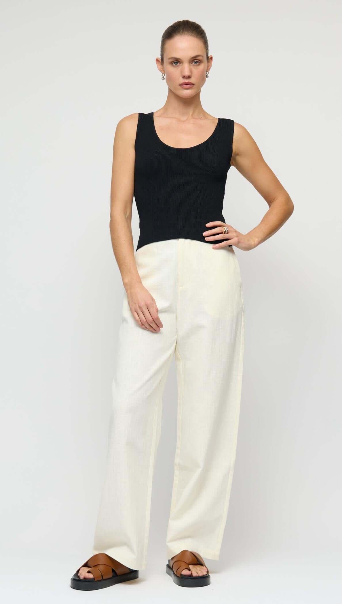 Reversible Black Knit Tank Top styled with cream wide-leg pants, showcasing scoop neckline and fitted silhouette.