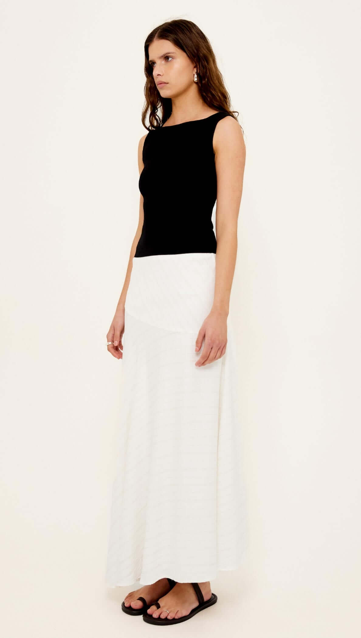 Model wearing Reversible Black Knit Tank Top with a white skirt, showcasing versatile scoop and boat neck styles.