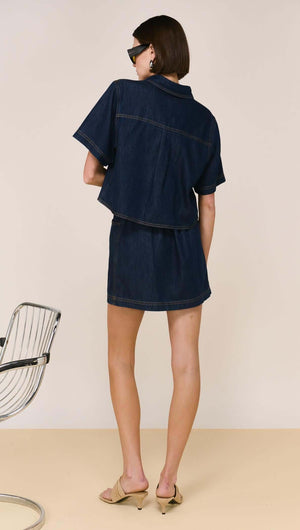 Denim Cropped Short-Sleeve Shirt displayed on a model, showcasing a structured cropped silhouette in dark denim.