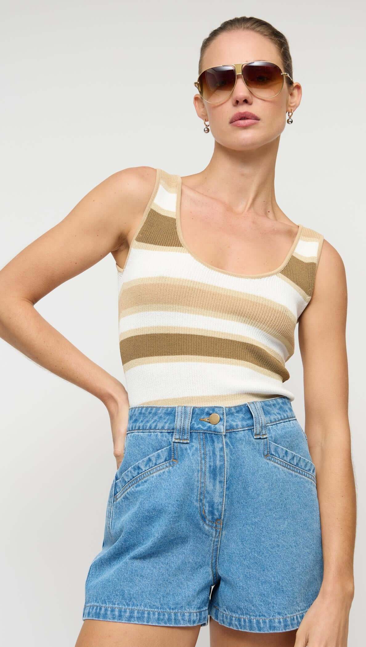 Model wearing NOA DENIM SHORTS paired with a striped tank top and sunglasses, showcasing a stylish summer outfit.