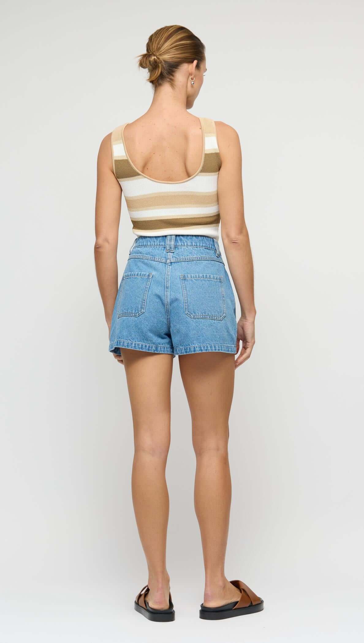 Back view of a woman wearing NOA DENIM SHORTS paired with a striped tank top, showcasing casual summer style.