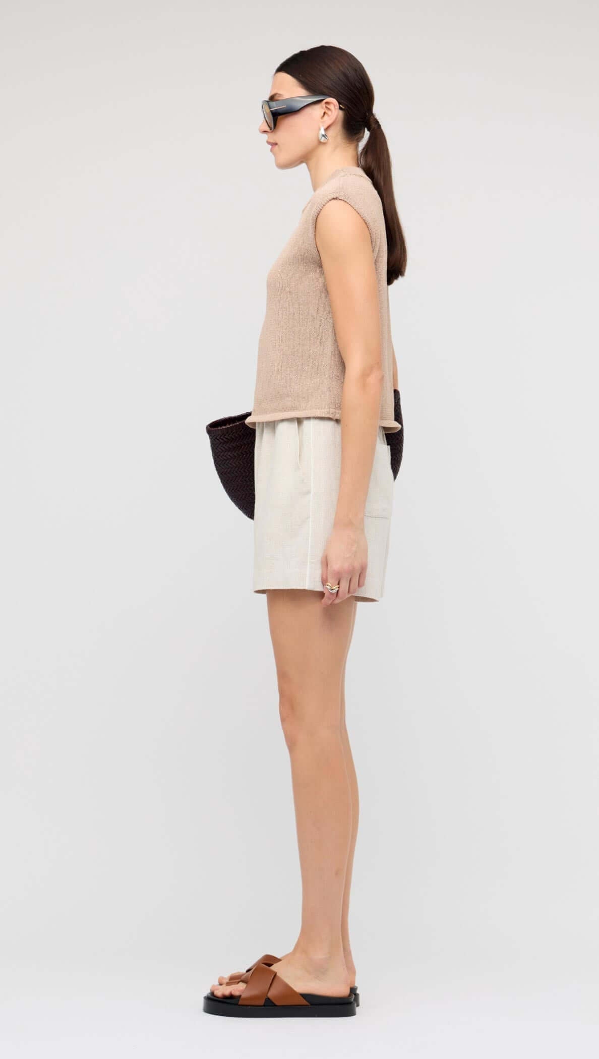 Model wearing Natural Marle Relaxed Linen Shorts with a beige top and accessories, showcasing side view and relaxed fit.