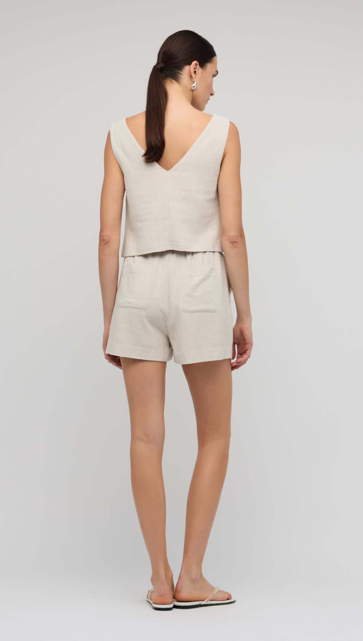 Woman wearing Natural Marle Relaxed Linen Shorts and matching V Back Top, showcasing a relaxed summer outfit.
