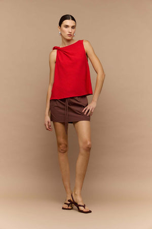 Model wearing a stylish red crepe twist top with a modern design paired with a brown mini skirt.