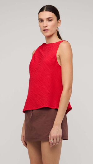 Model wearing a vibrant red crepe twist top paired with brown shorts, showcasing a stylish and modern design.