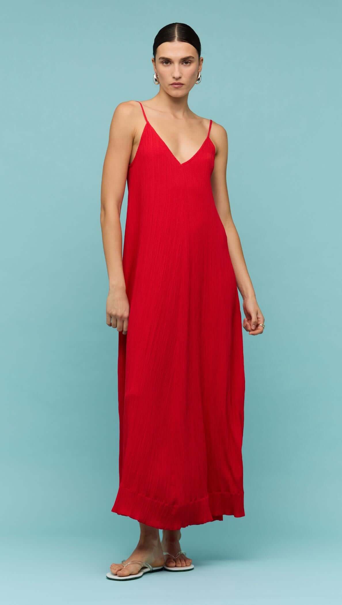 Model wearing a red crepe V-neck floaty maxi dress against a light blue background.