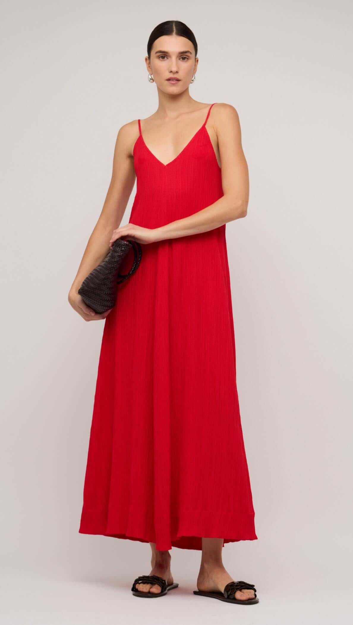 Model wearing a red crepe V-neck floaty maxi dress against a light blue background.