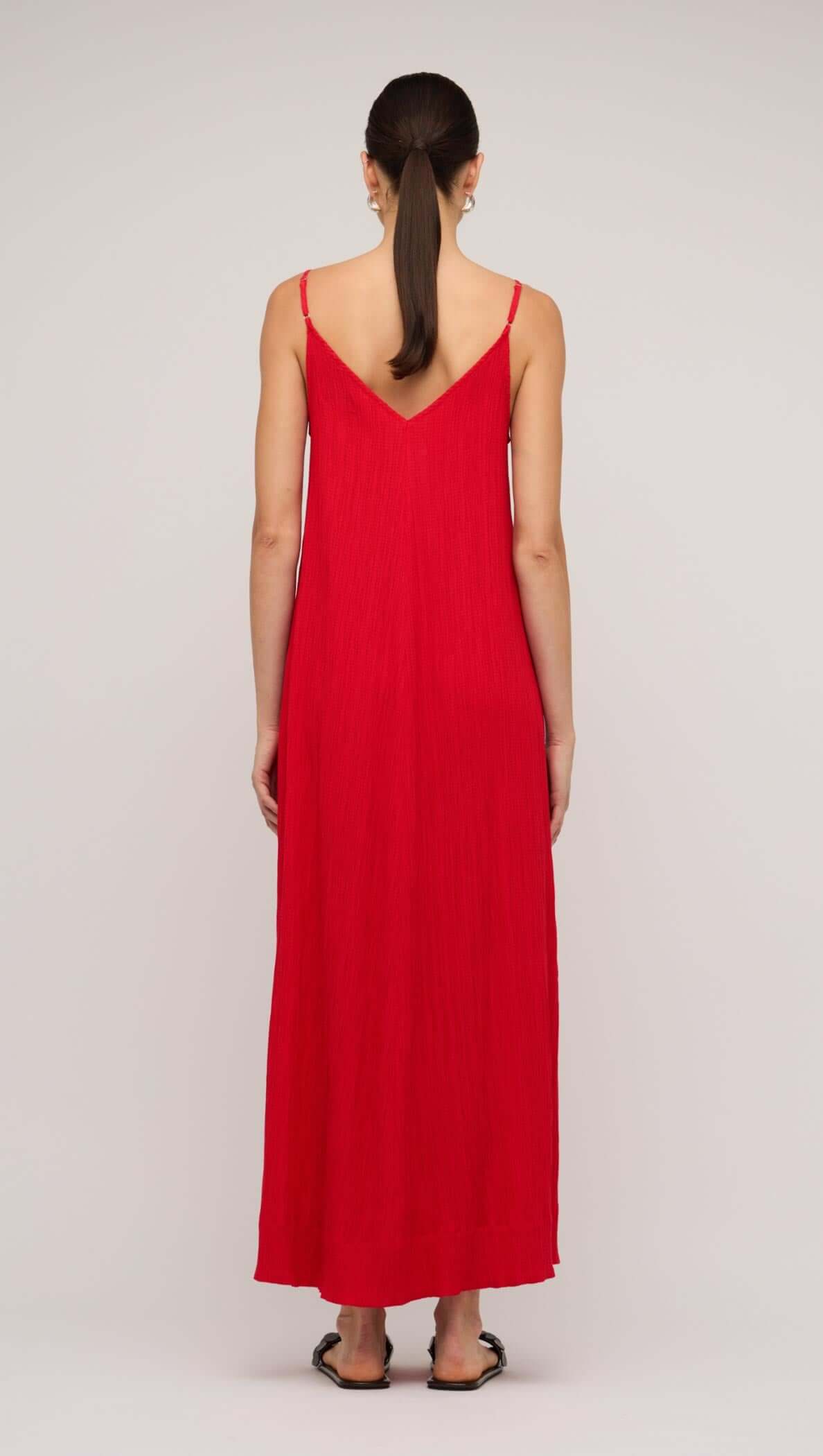 Back view of a woman wearing a red crepe V-neck floaty maxi dress, showcasing its elegant design and flow.