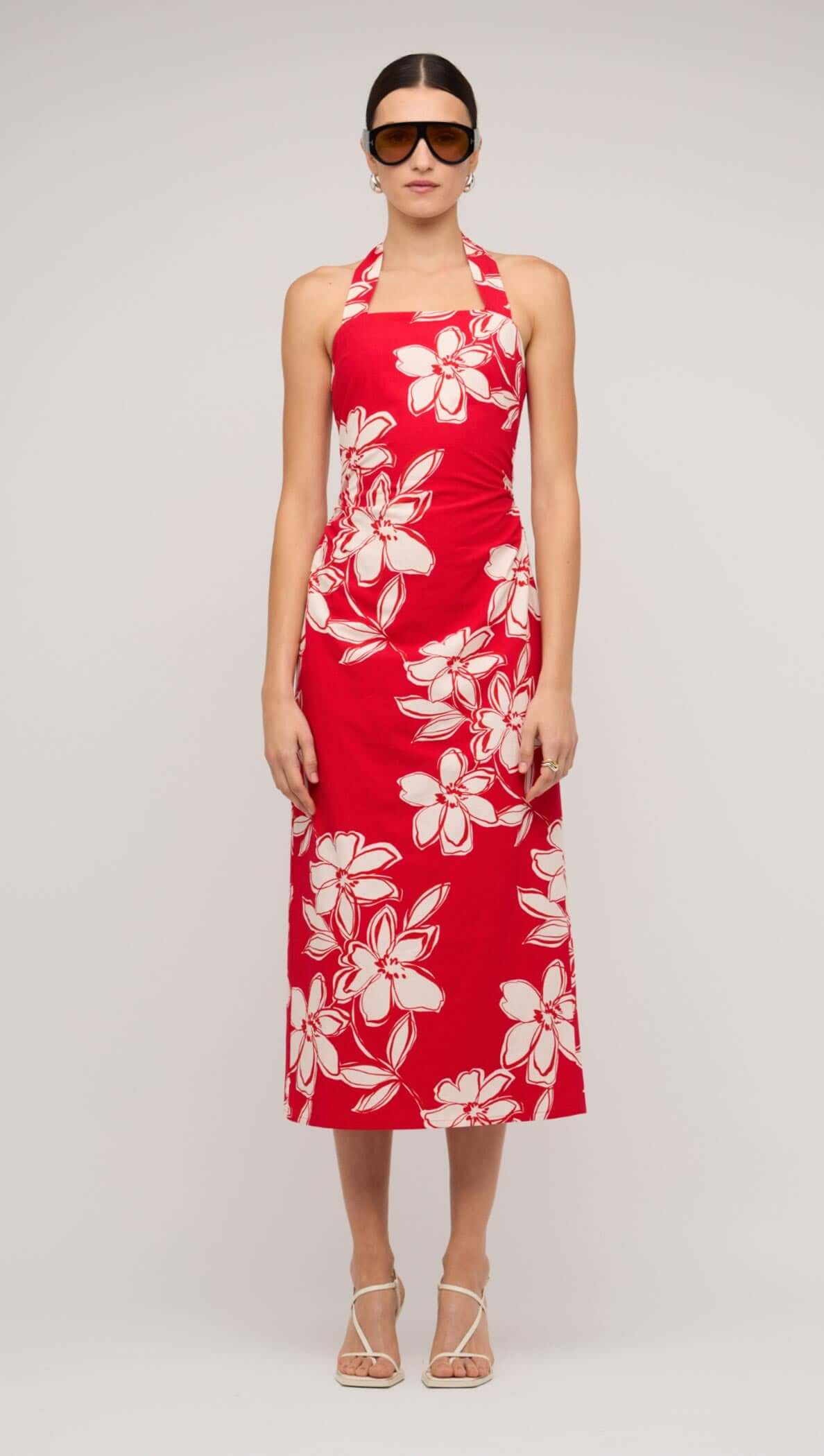 Model wearing a red and white floral halter-neck midi dress with stylish sunglasses.