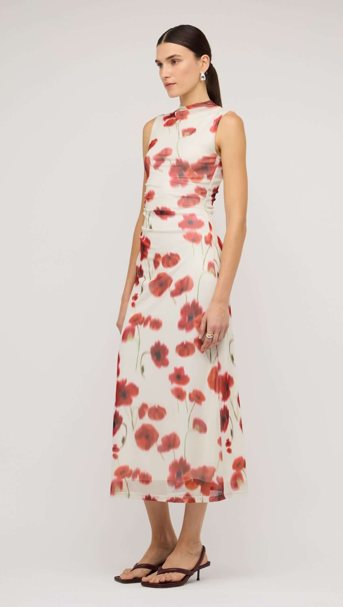 Model wearing a red and white poppy print mesh midi dress, showcasing a floral pattern with a chic design.
