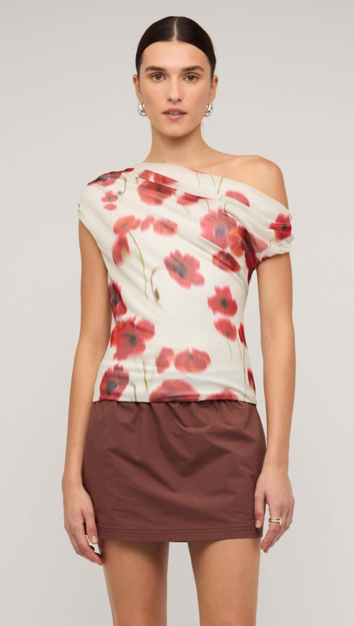 Red and white poppy print off-shoulder mesh top worn with a brown mini skirt, showcasing floral design and stylish fit.