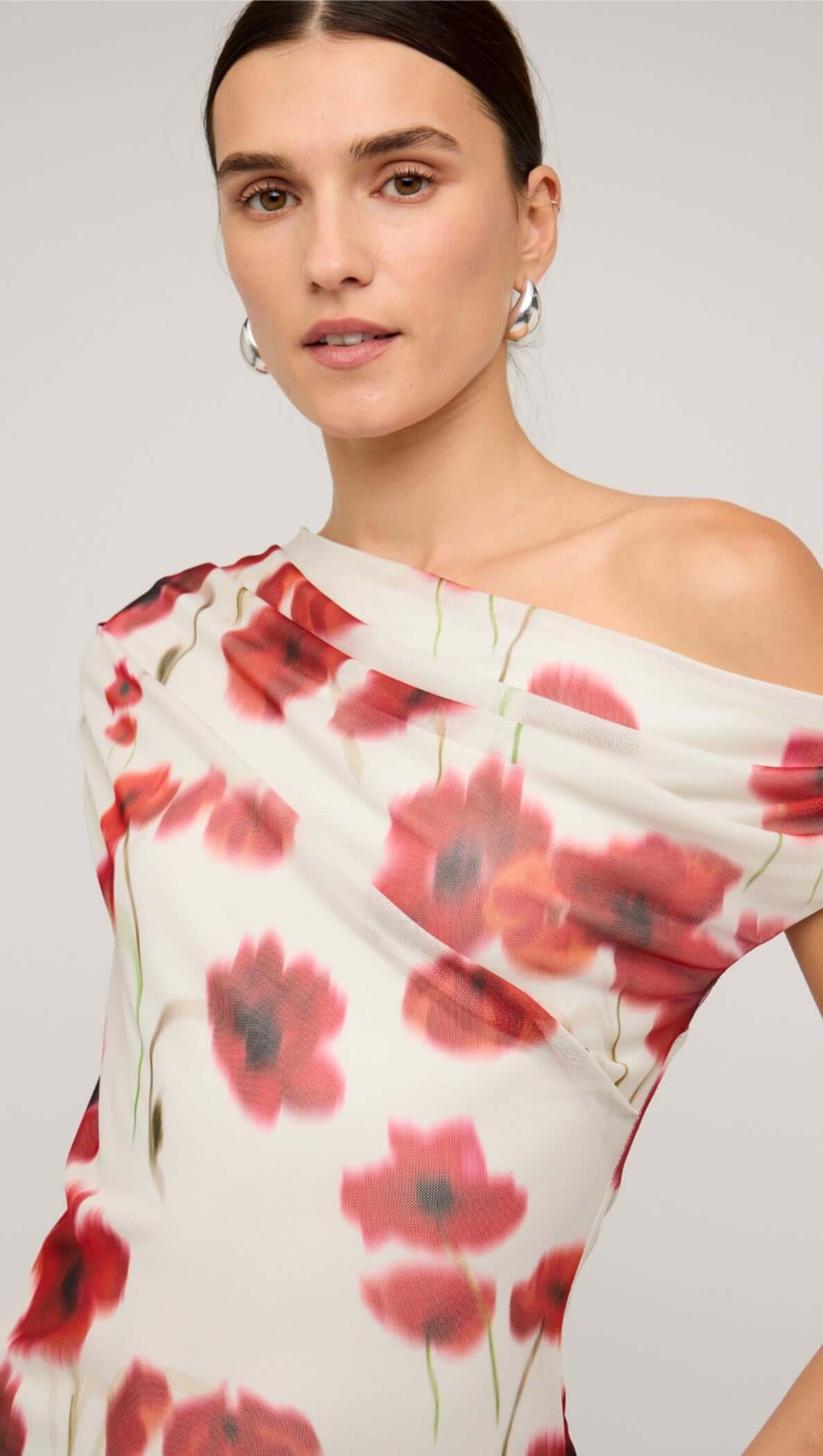 Red and white poppy print off-shoulder mesh top worn with a brown mini skirt, showcasing floral design and stylish fit.
